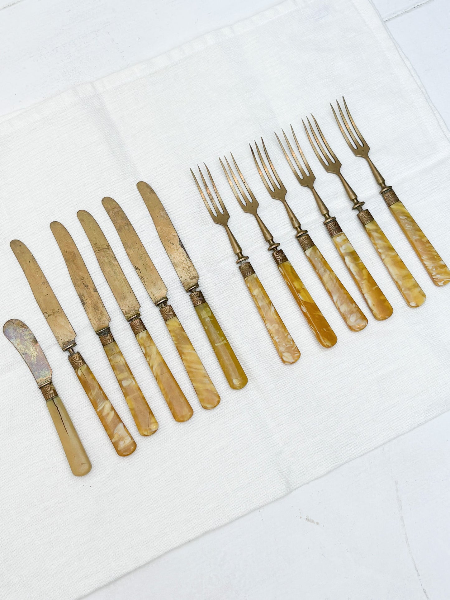 Set of vintage knives and forks with pearlized handles on a white surface