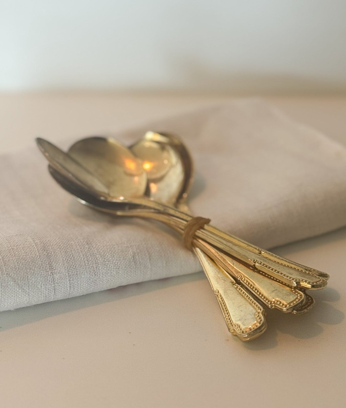 Set of gold spoons on a light gray napkin with a white background