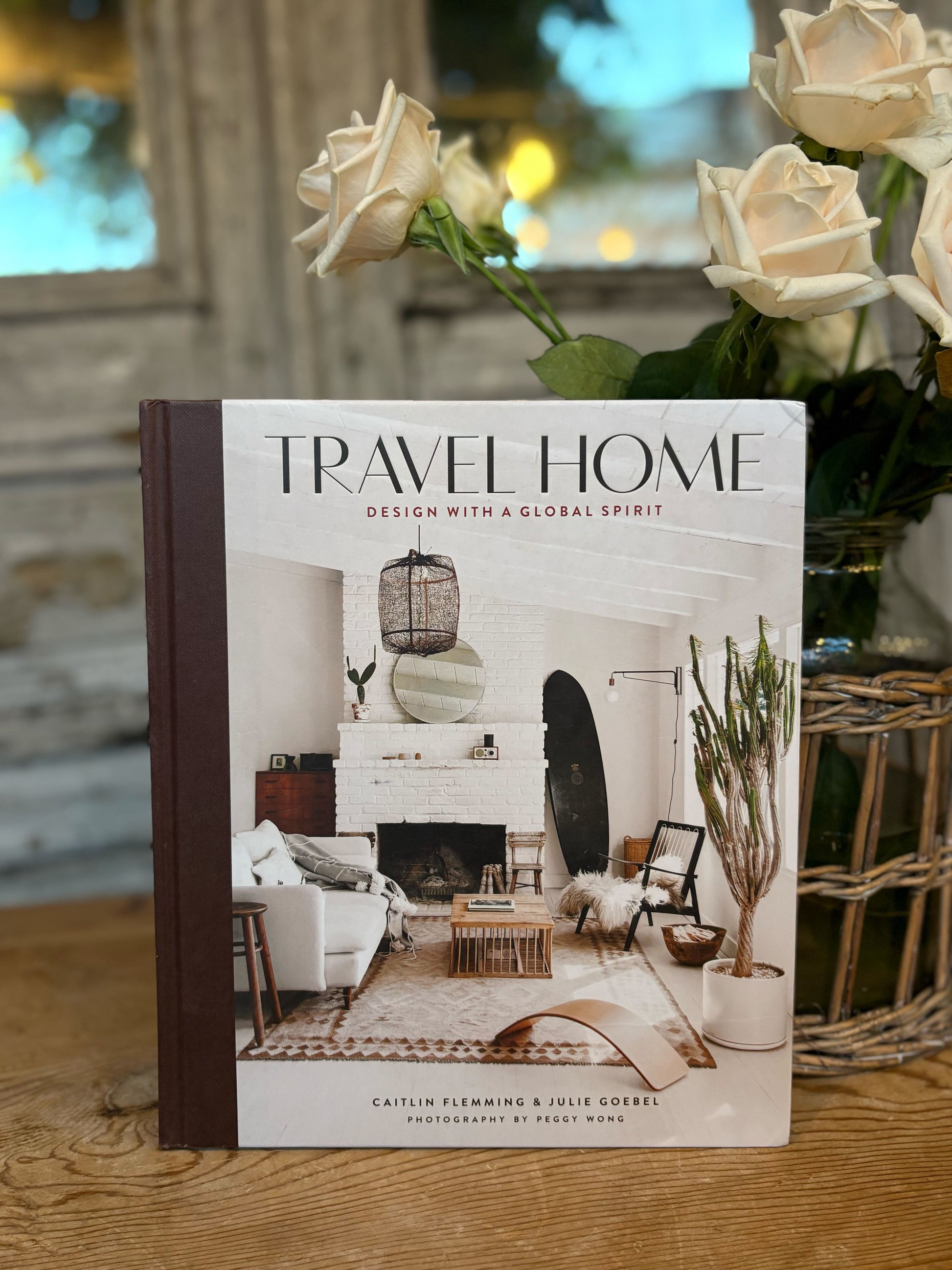 Book titled 'Travel Home' on a wooden surface with flowers in the background