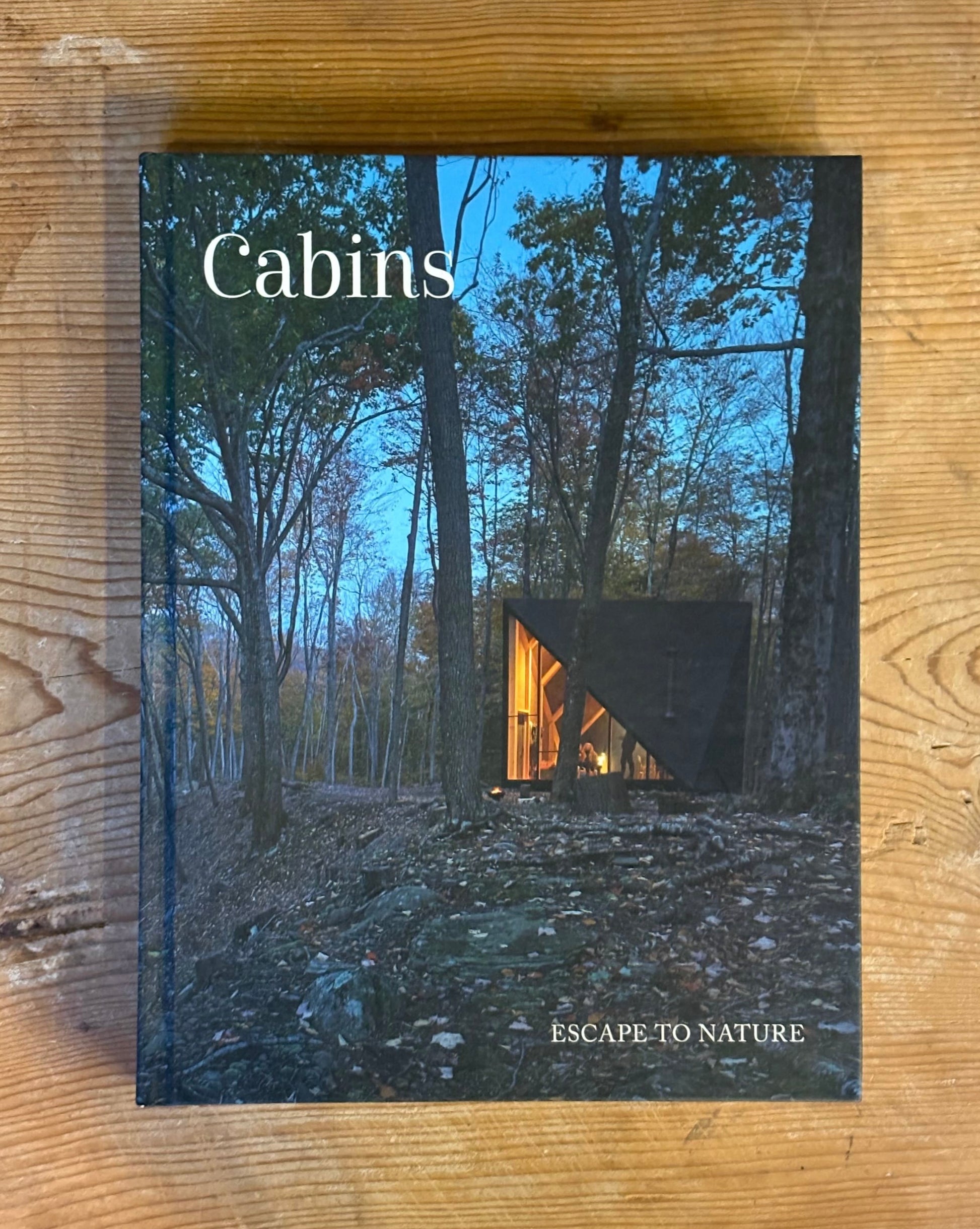 Book titled 'Cabins: Escape to Nature' on a wooden surface