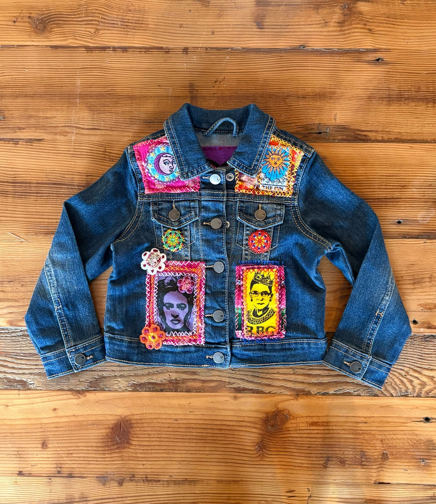 Denim jacket with colorful patches on a wooden surface