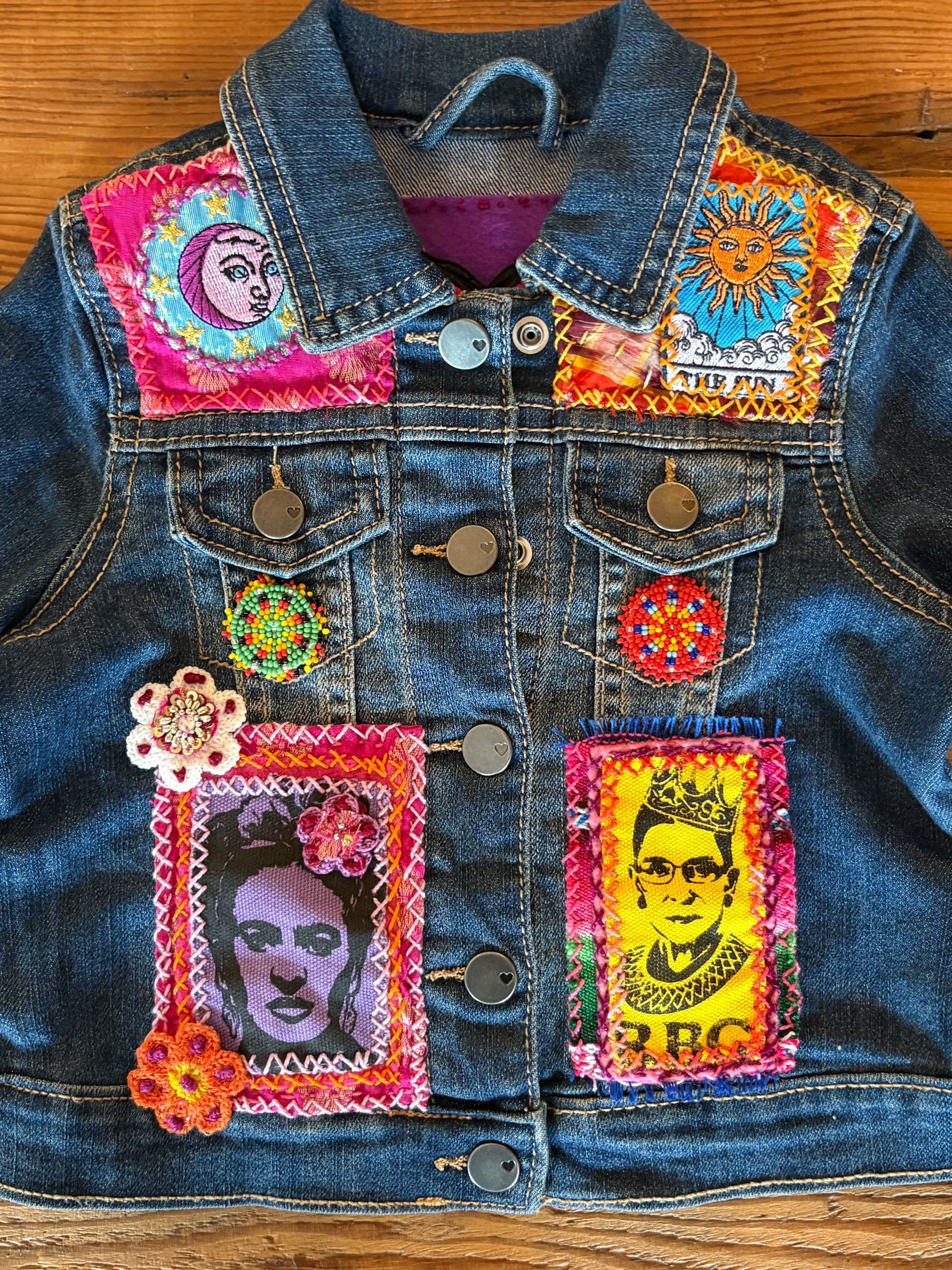 Denim jacket with colorful patches and appliqués on a wooden surface