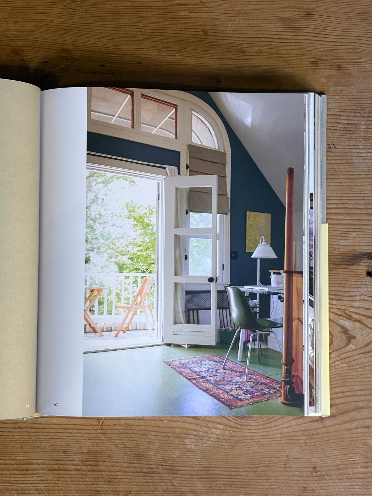 Open book showing an interior design page with a room featuring a staircase and large windows.
