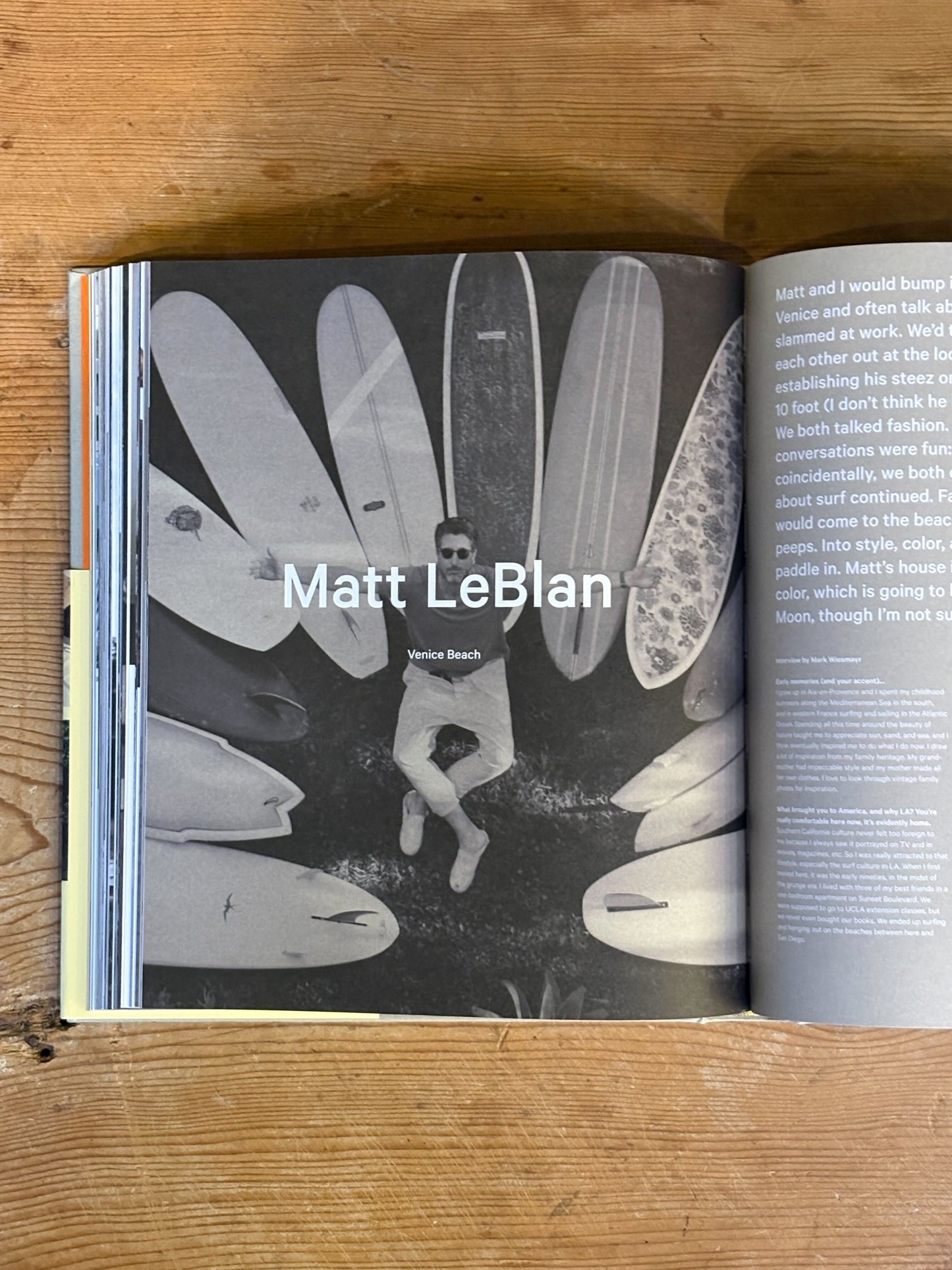 Open book on a wooden surface with a black and white illustration of a person and surfboards.