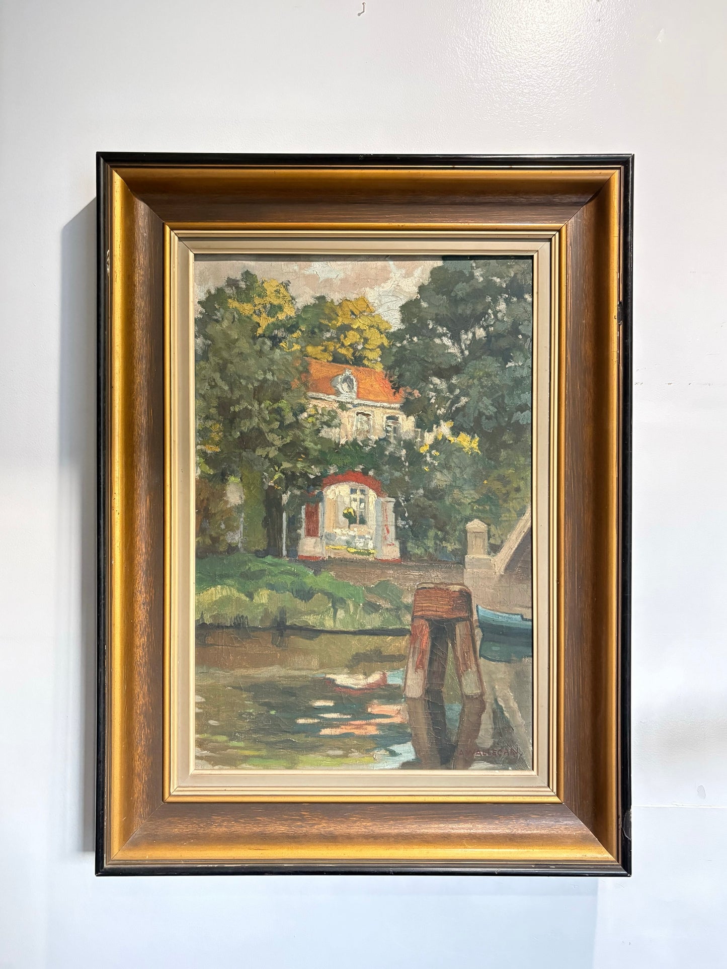 Framed painting of a scenic landscape with trees and a building.