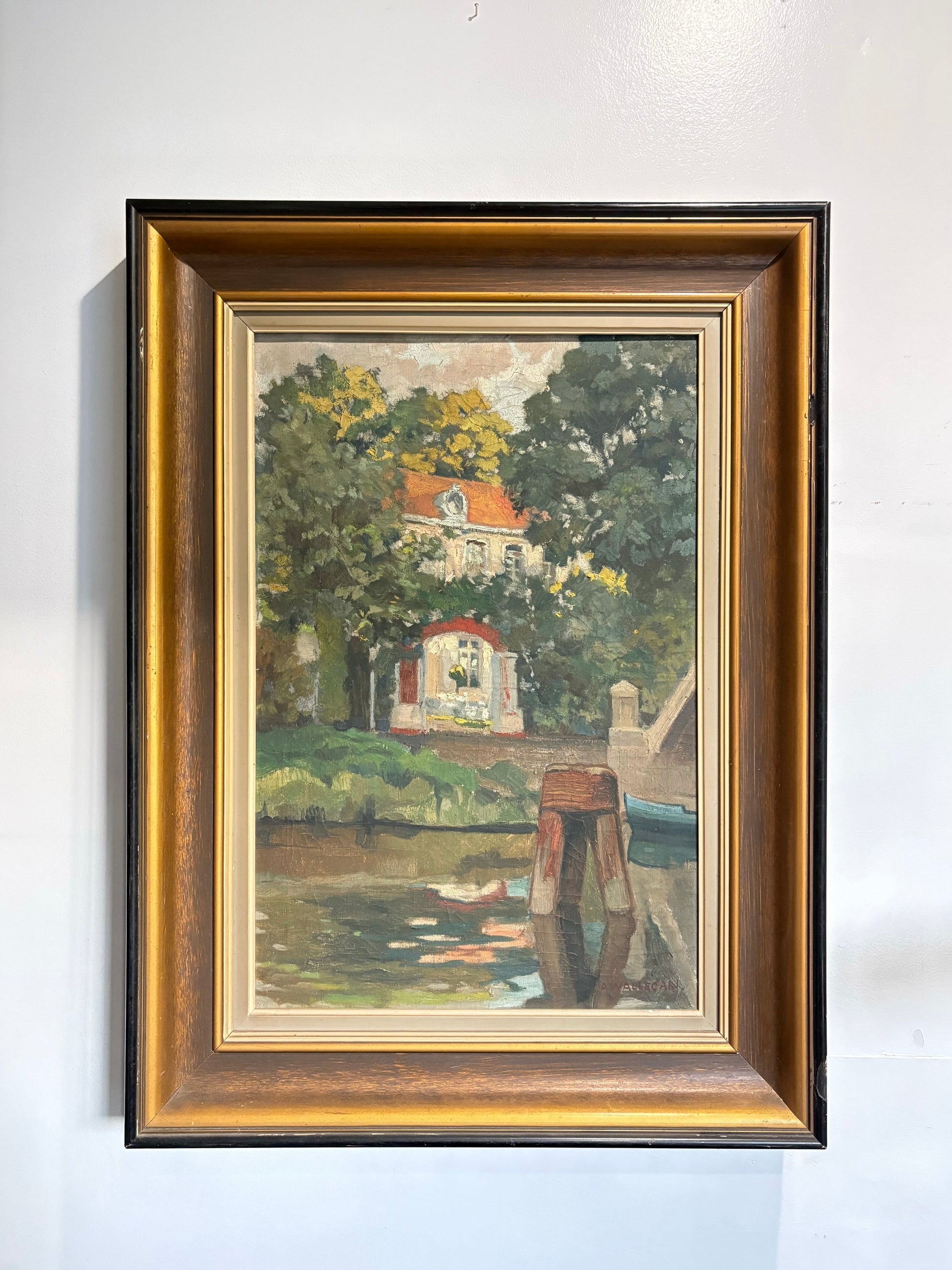 Framed painting of a scenic landscape with trees and a building.