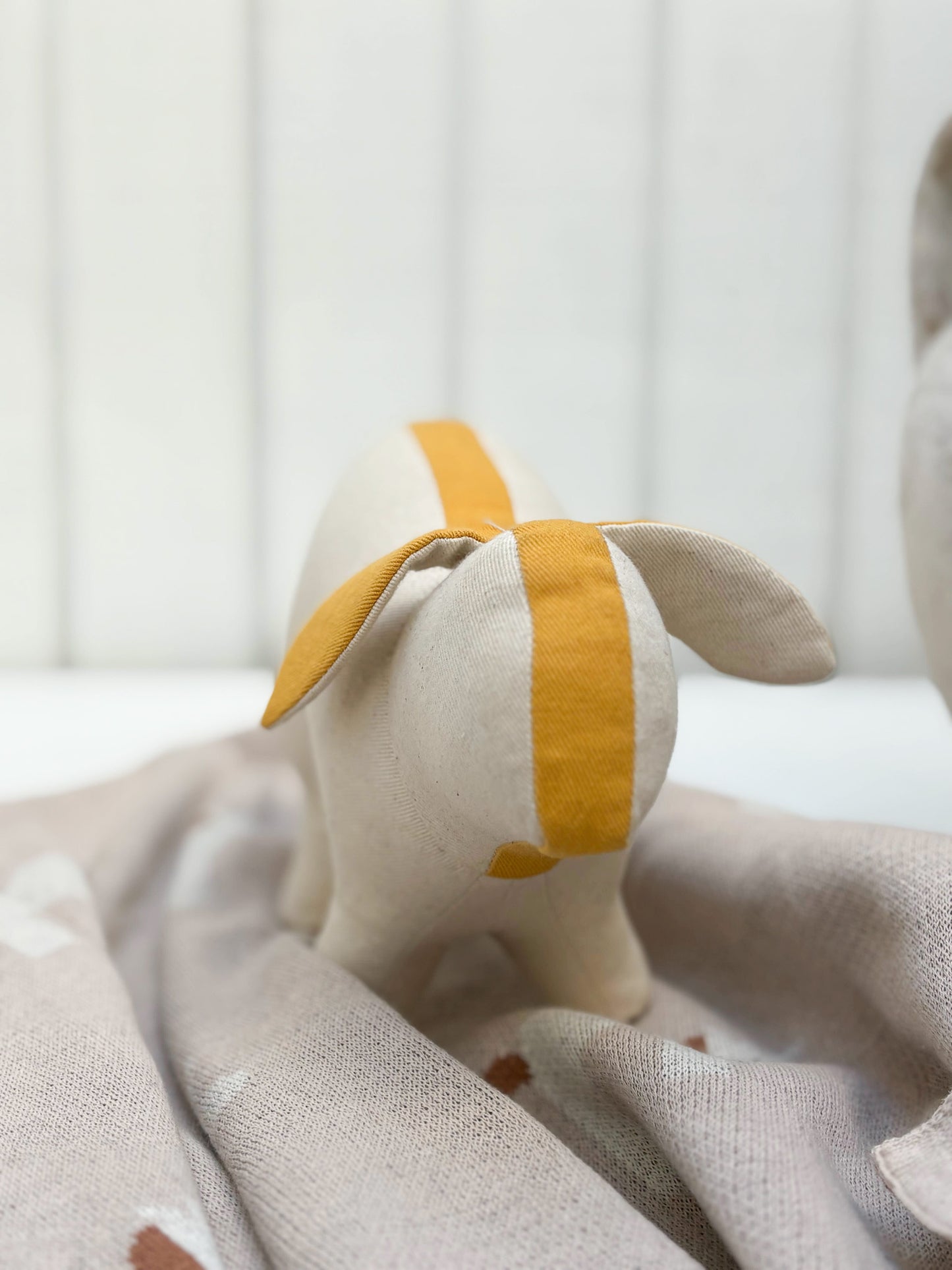 Small plush toy with a yellow stripe on a textured surface