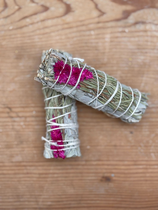 Bundled sage with pink flowers on a wooden surface