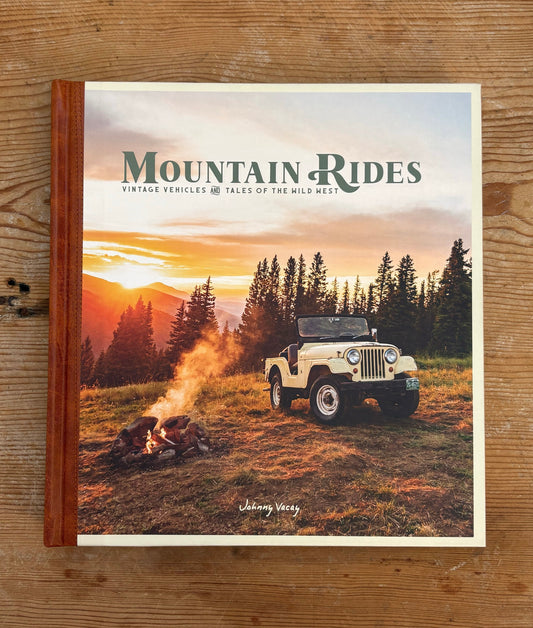 Book titled 'Mountain Rides' with a jeep and sunset scene on the cover, placed on a wooden surface.