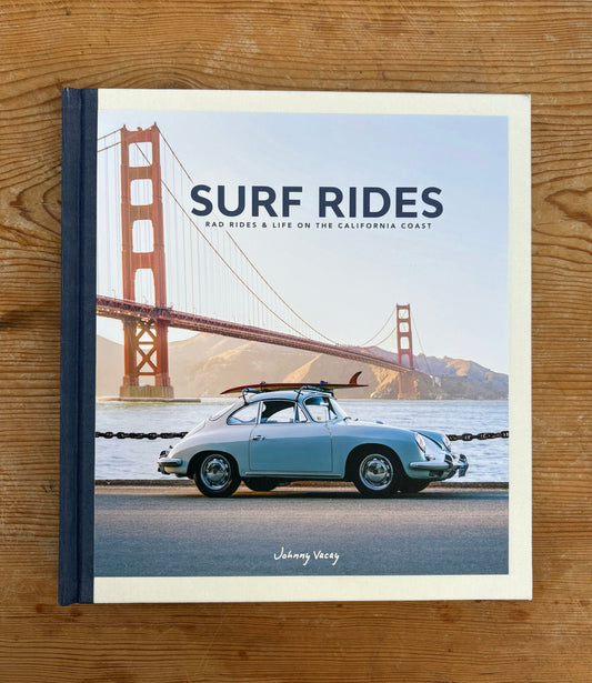 Book titled 'Surf Rides' with a car and Golden Gate Bridge on the cover, placed on a wooden surface.