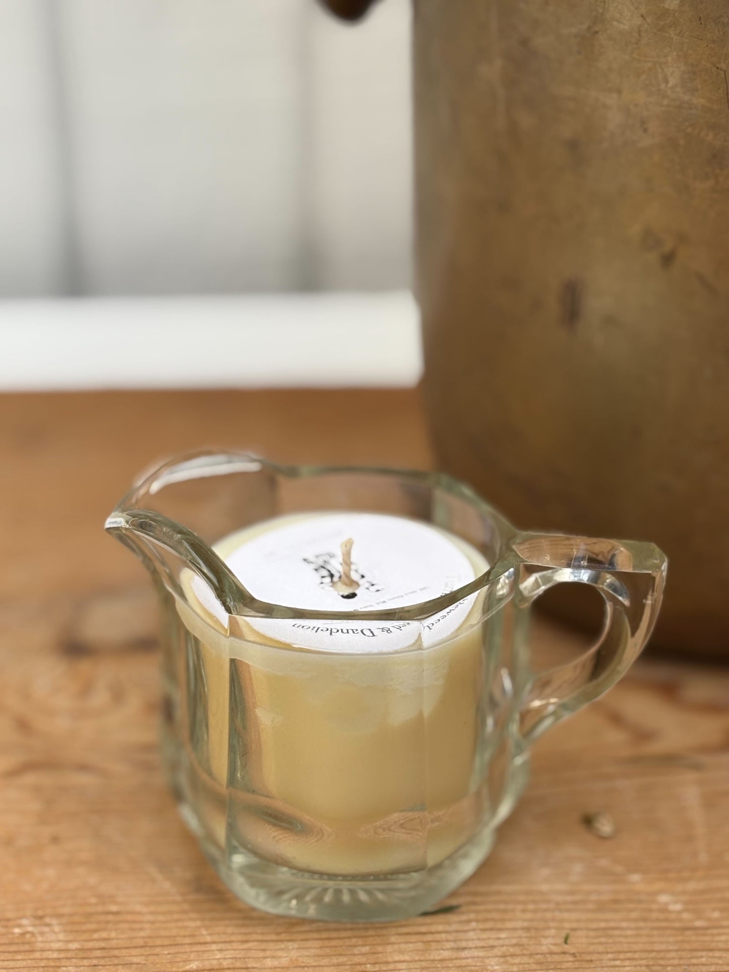 Candle in a glass pitcher on a wooden surface