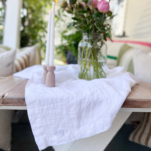 linen white table cloth on wood table with pink flowers and taper candles