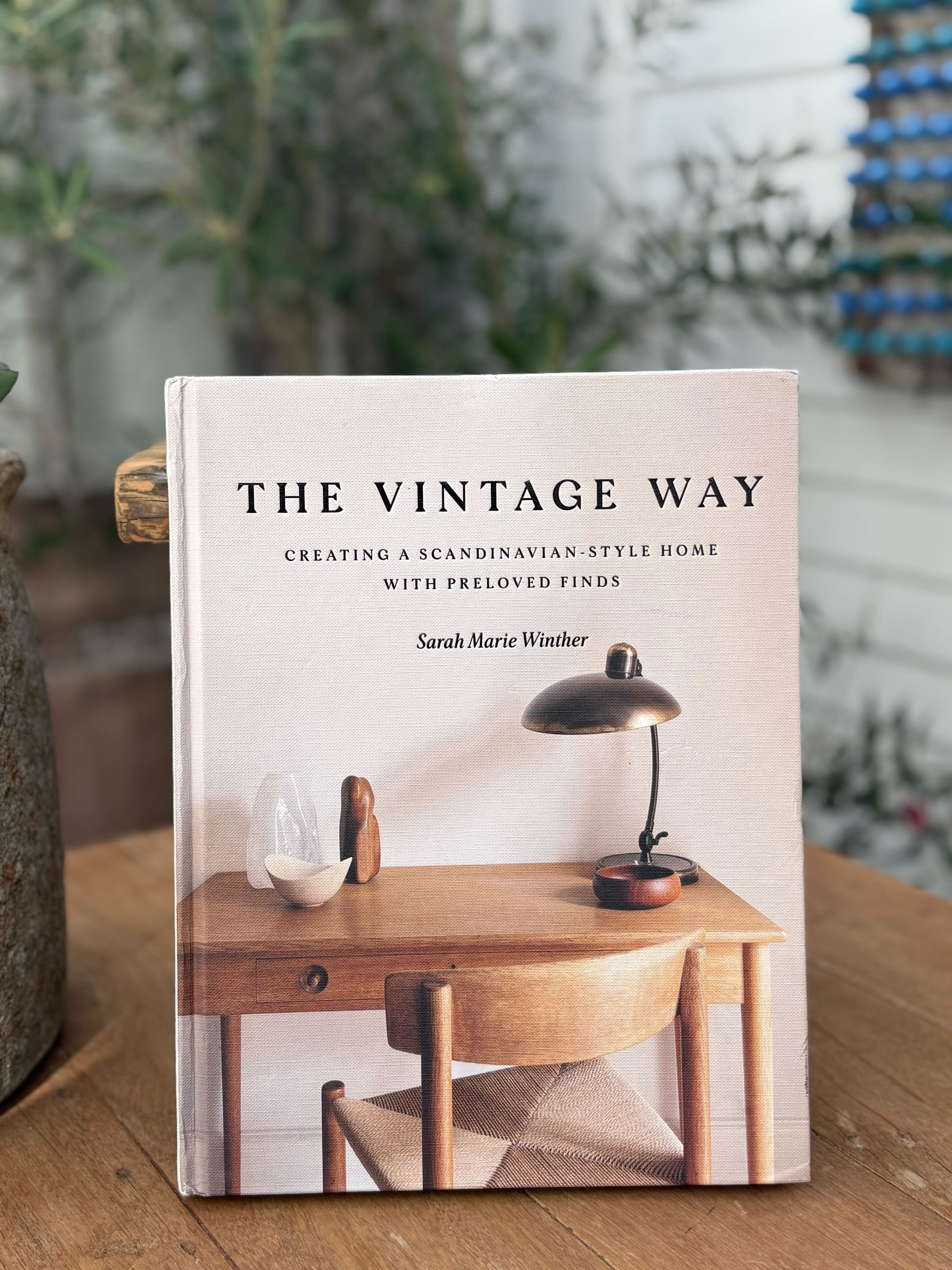 Book titled 'The Vintage Way' by Sarah Marie Winther on a wooden surface with a blurred indoor background.