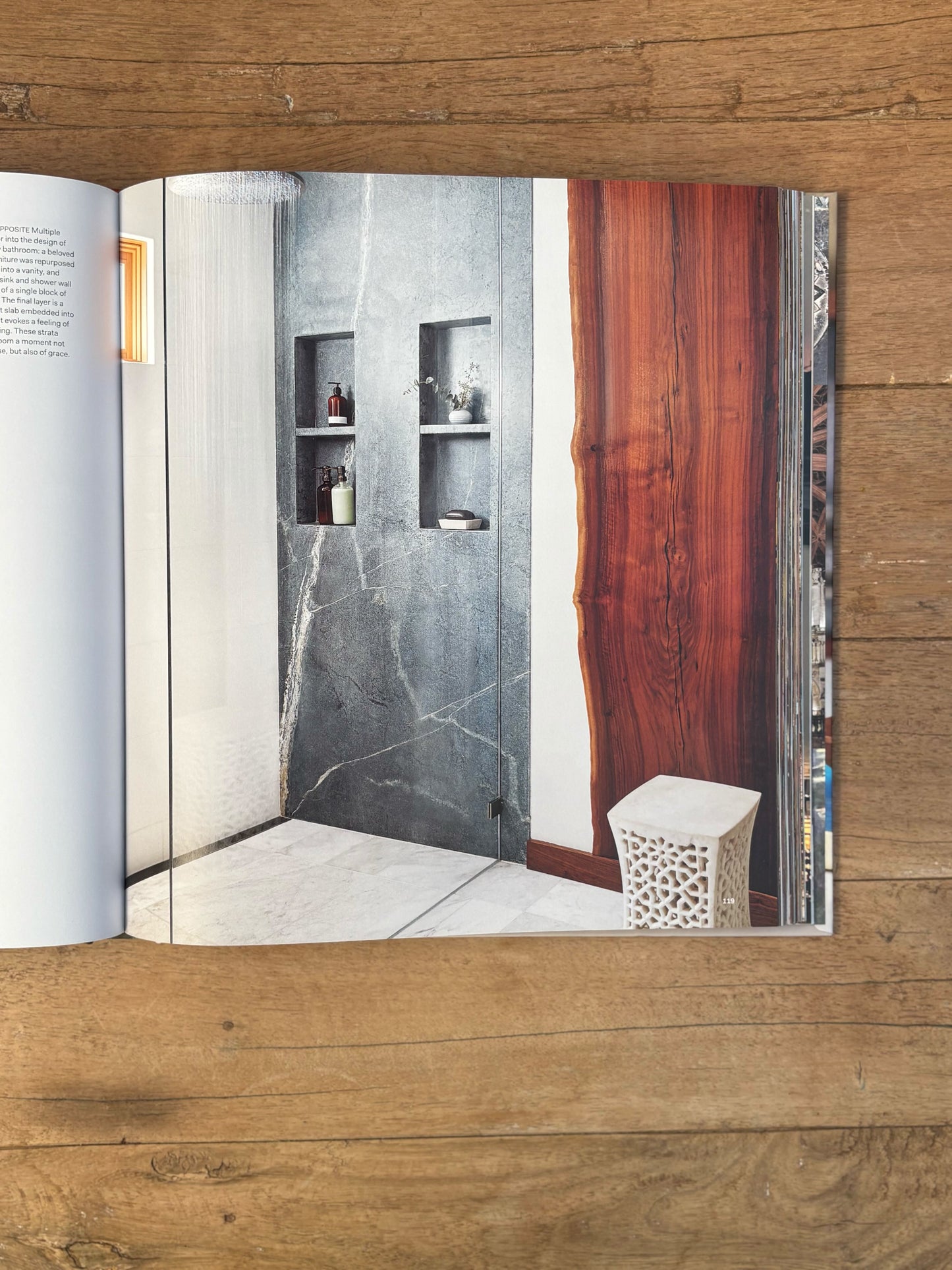 Open book showing a bathroom interior with marble walls and wooden door.