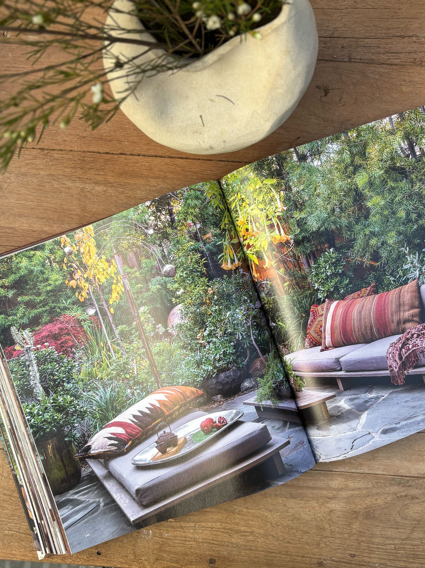 Open book showing a garden scene with a table and chairs on a wooden surface.