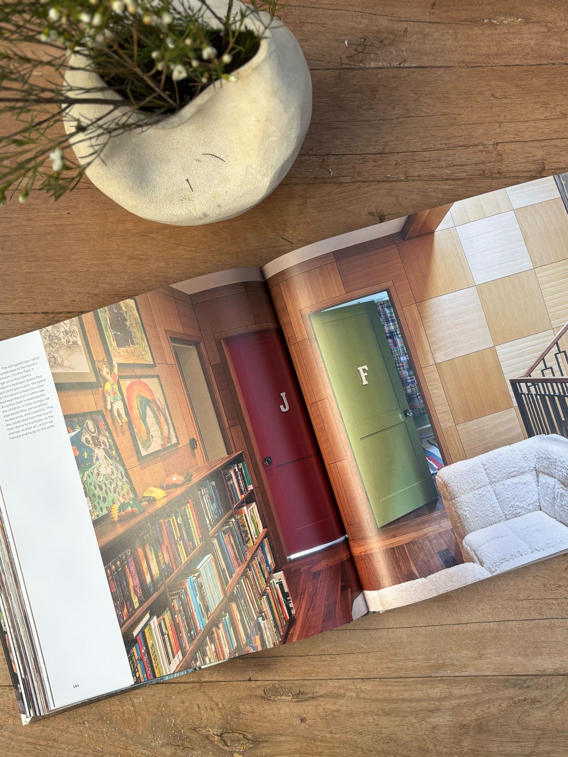 Open book on a wooden surface with a plant in the corner