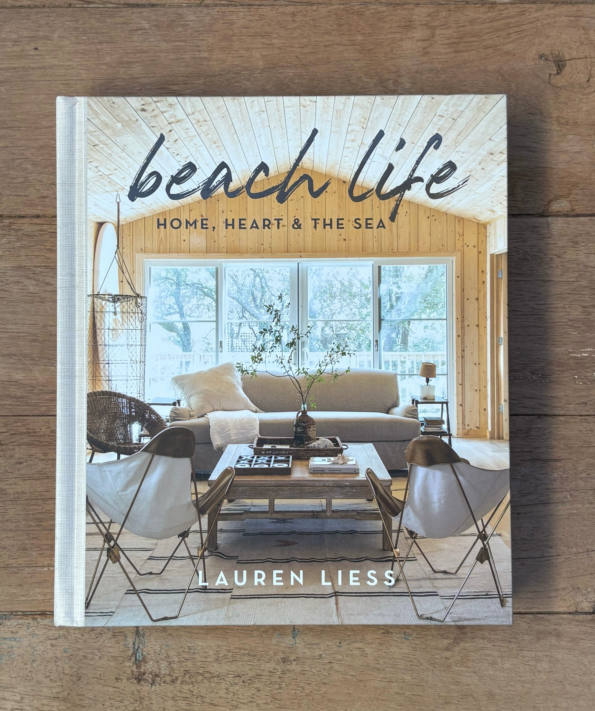 Book titled 'beach life: Home, Heart & The Sea' by Lauren Liess on a wooden surface