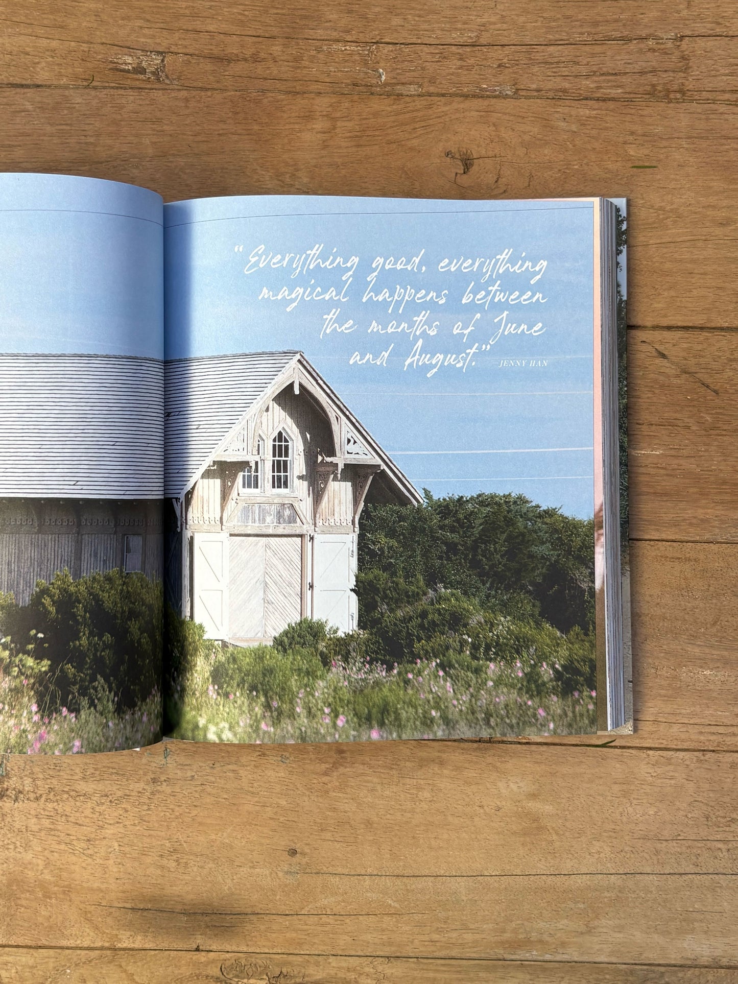 Open book on a wooden surface with a scenic image of a house and text.