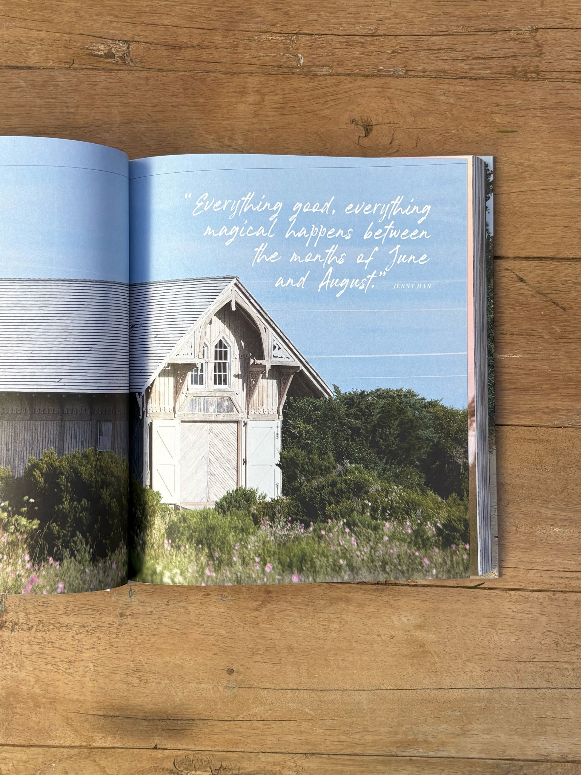 Open book on a wooden surface with a scenic image of a house and text.