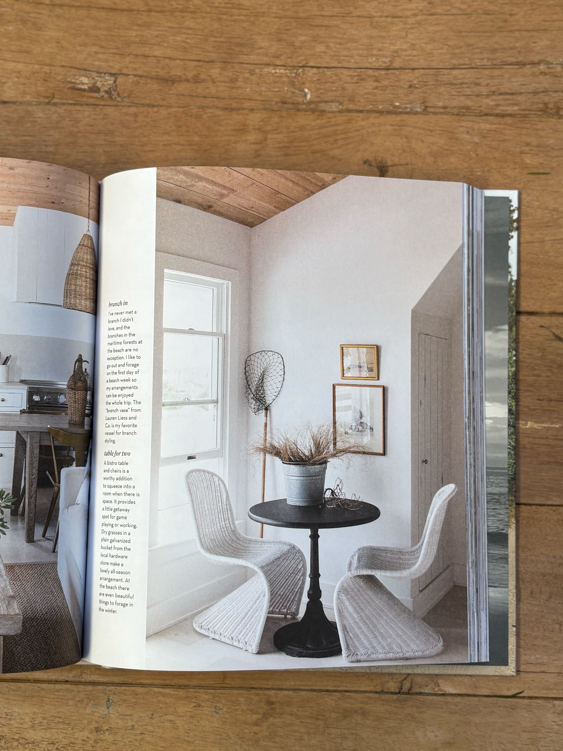 Open book showing a interior design layout with chairs and a table on a wooden surface.