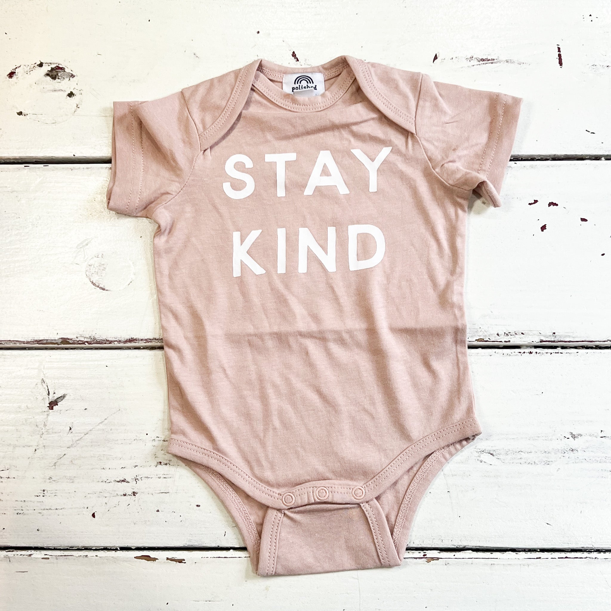 light pink baby onesie with STAY KIND in white on front