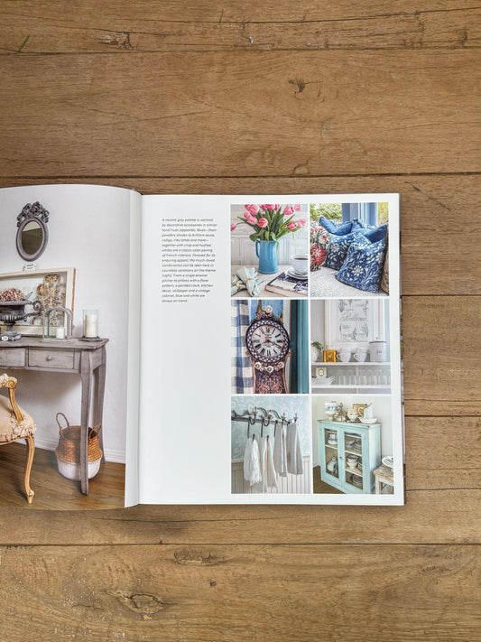 Open book on a wooden surface with interior design images and text.