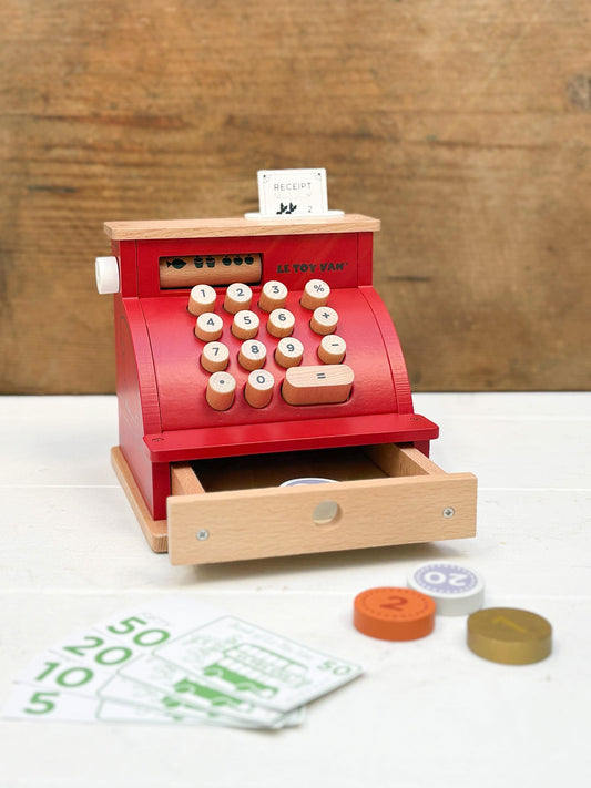 Wooden toy cash register with coins and money on a wooden background
