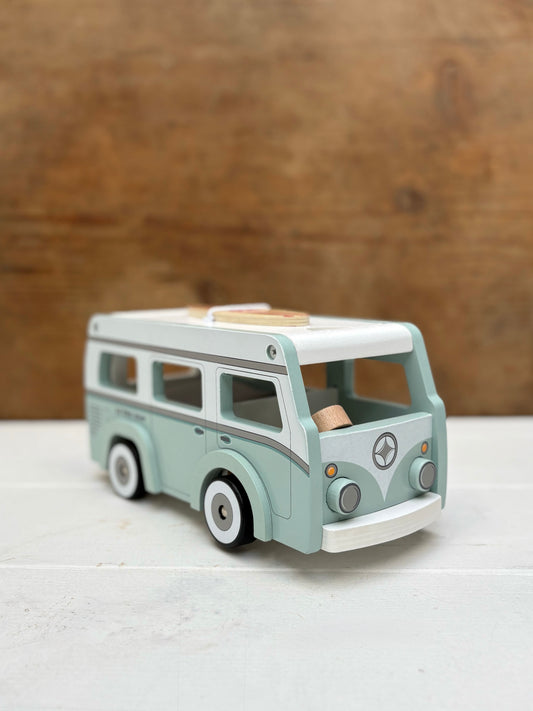 Toy van on a white surface with a wooden background