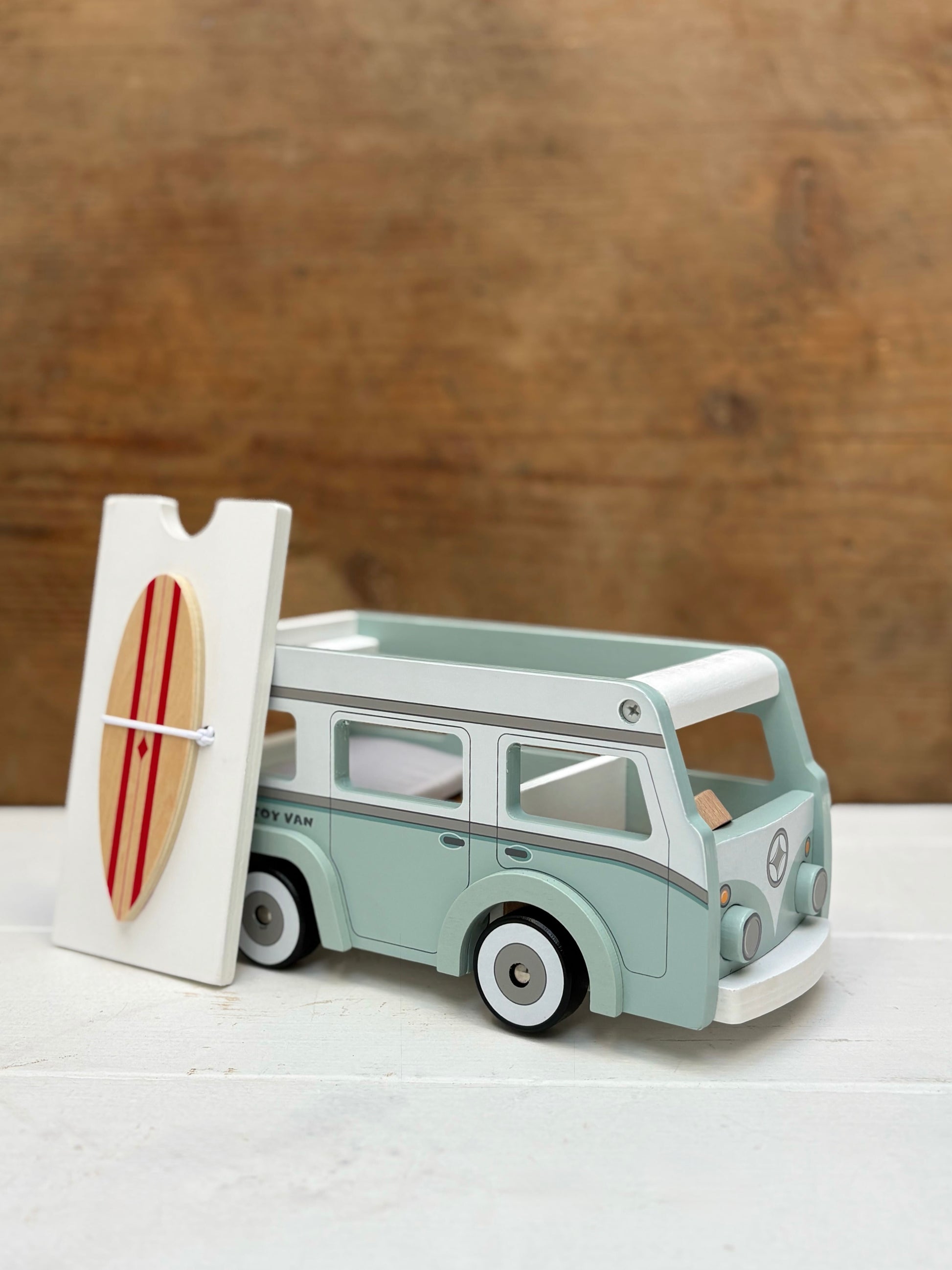 Model of a vintage van with a surfboard on a wooden background