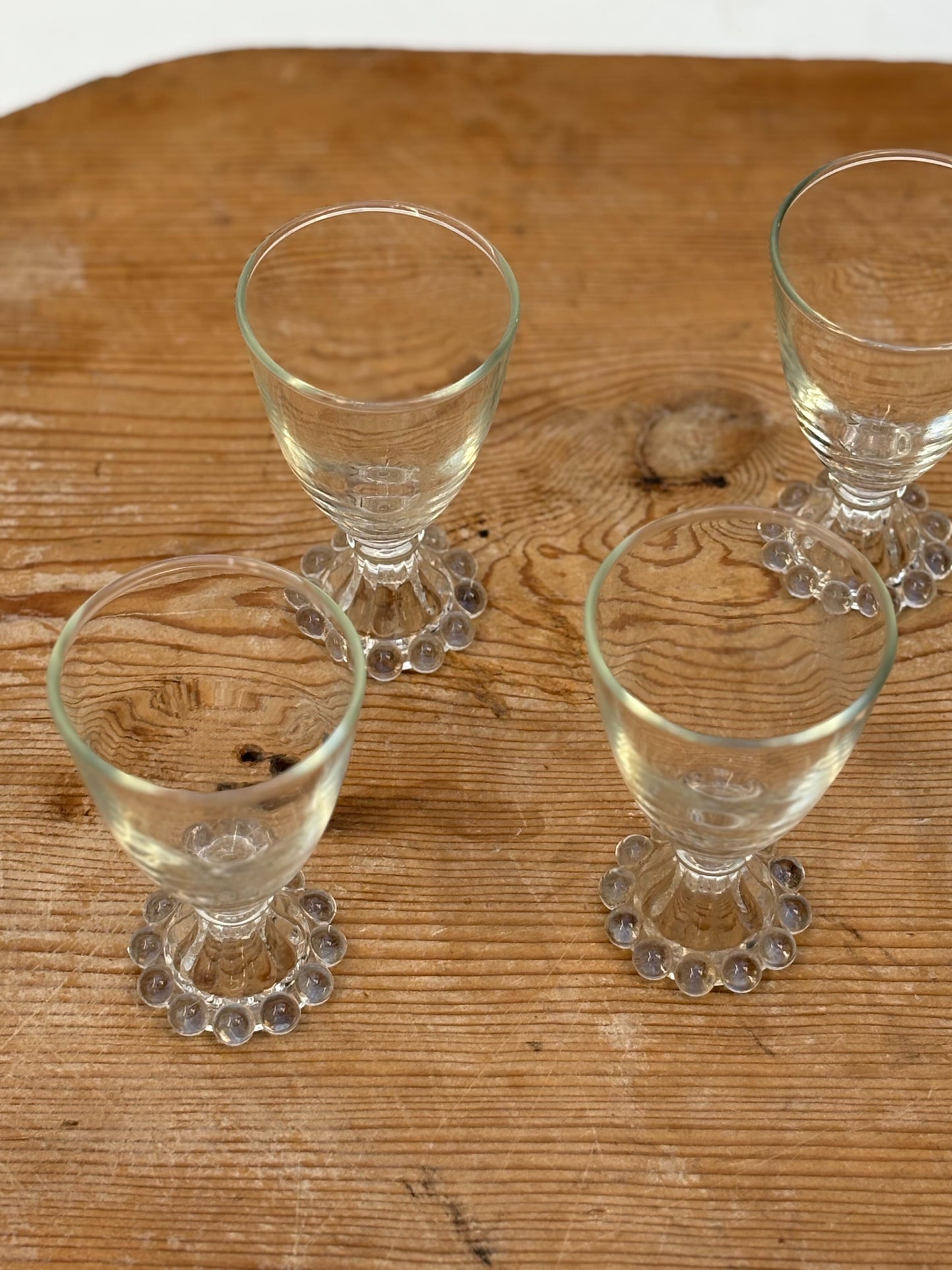 Four clear glass tumblers with decorative bases on a wooden surface