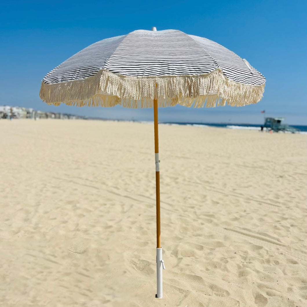 blue and white striped beach umbrella with fringe