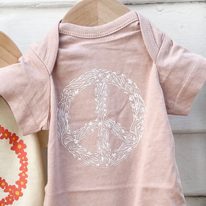 light pink onesie with white floral peace sign