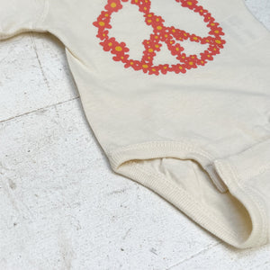 cream colored onesie with orange floral peace sign