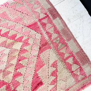 small area rug with geometric type patterns in reds, pinks and off white