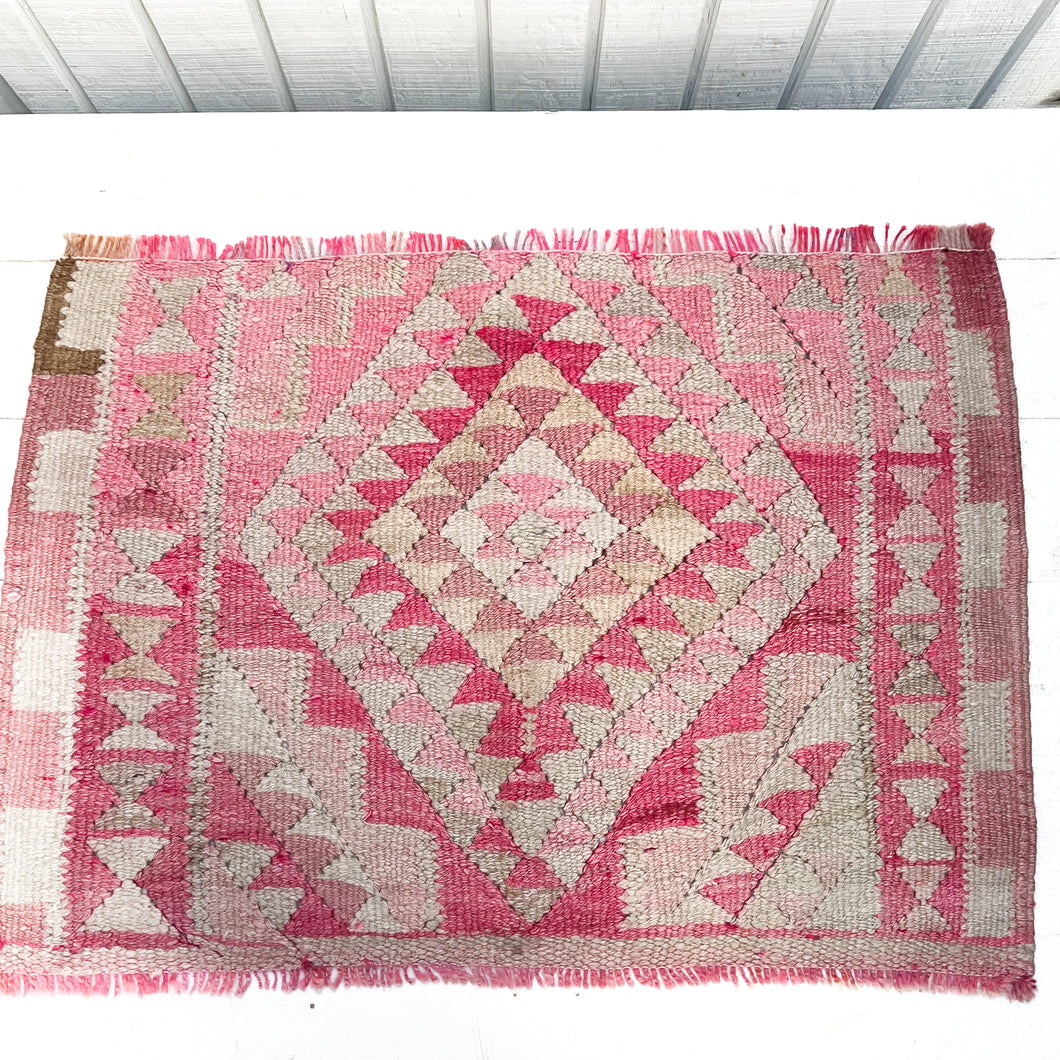 small area rug with geometric type patterns in reds, pinks and off white