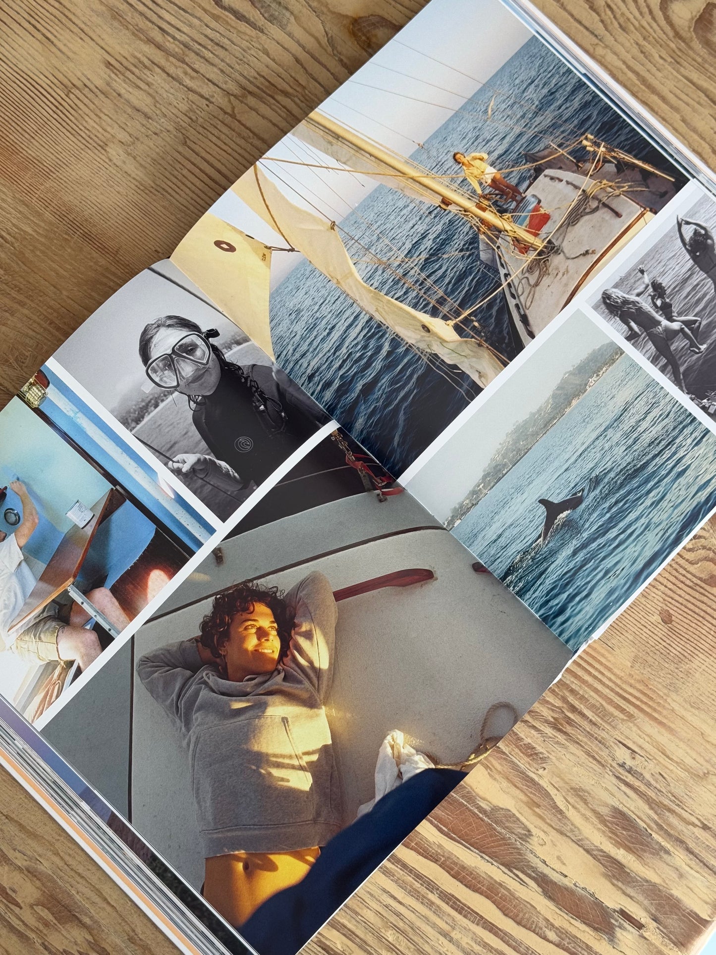 Open photo album with various images of people and activities on a wooden surface