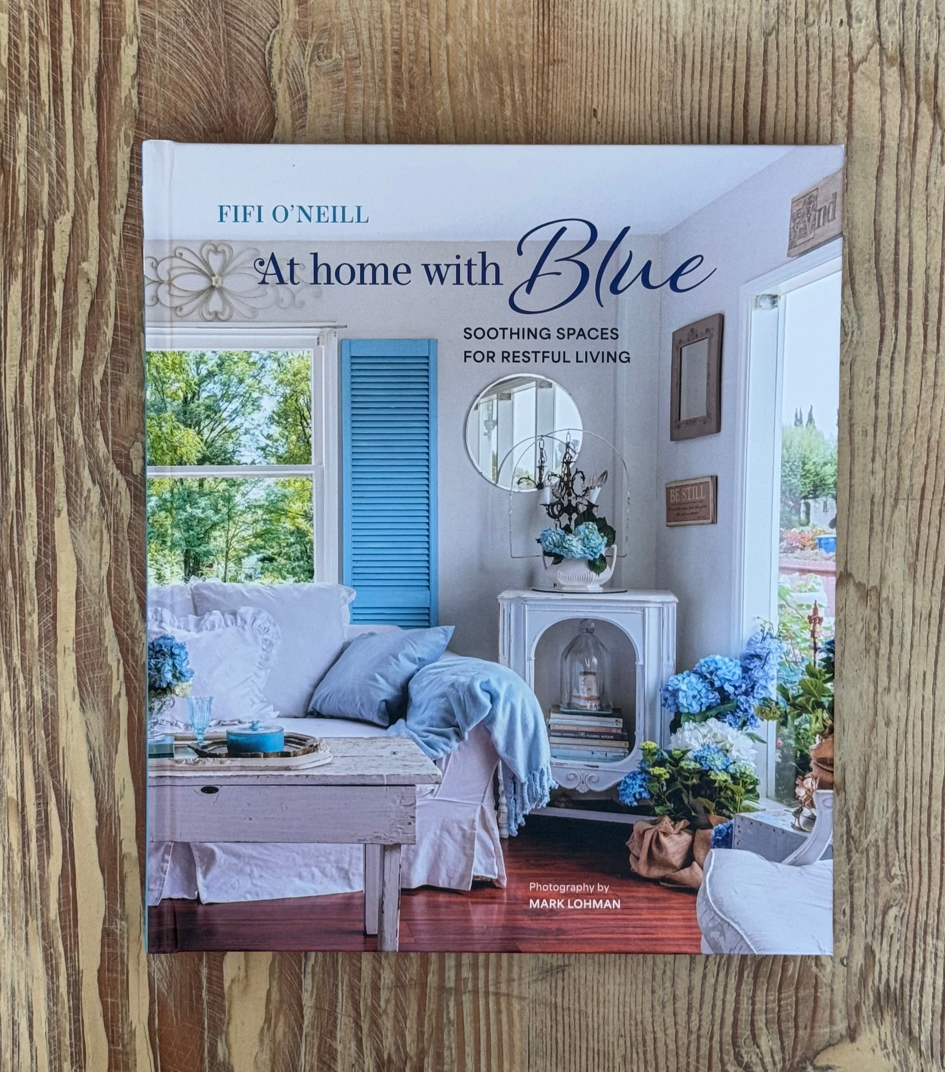 Book cover of 'At Home with Blue' by Fifi O'Neill on a wooden surface