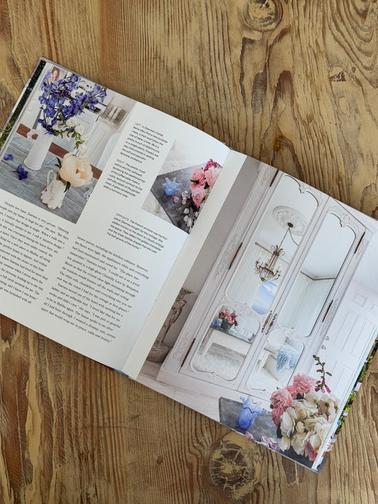 Open book on a wooden surface with floral arrangements and text.