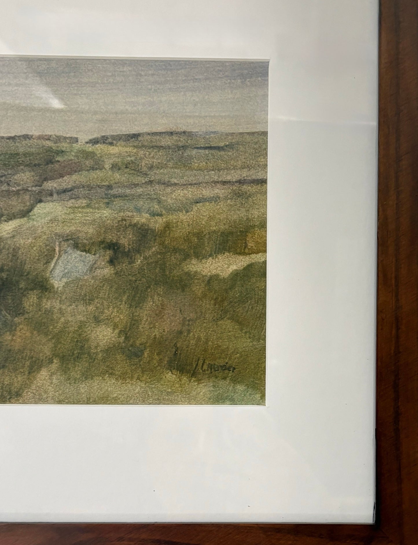 Framed watercolor landscape painting on a white wall