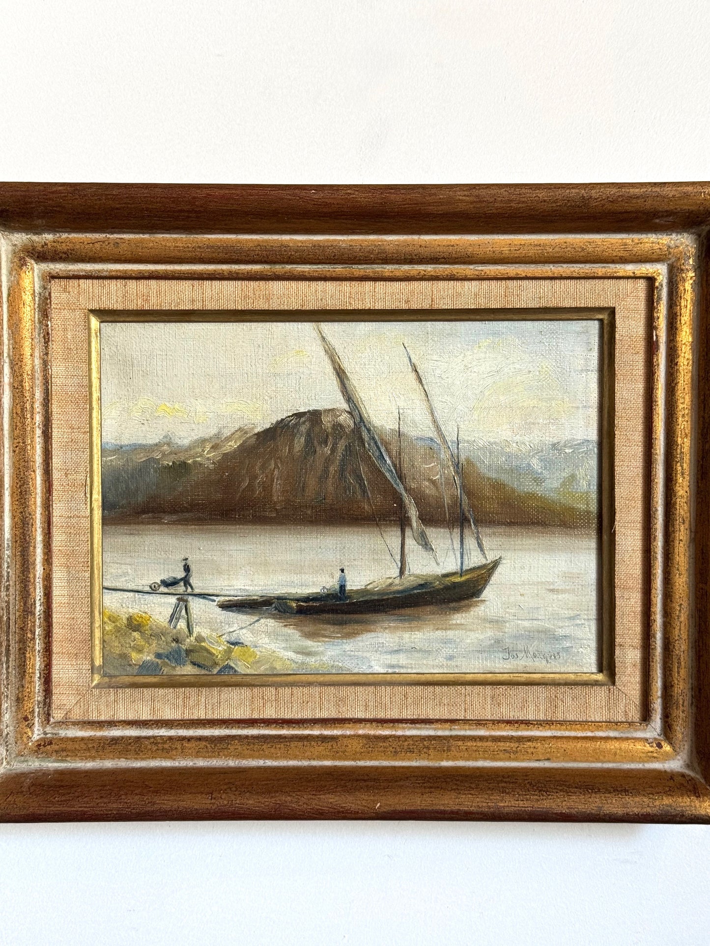 Framed painting of a sailboat on a lake with mountains in the background