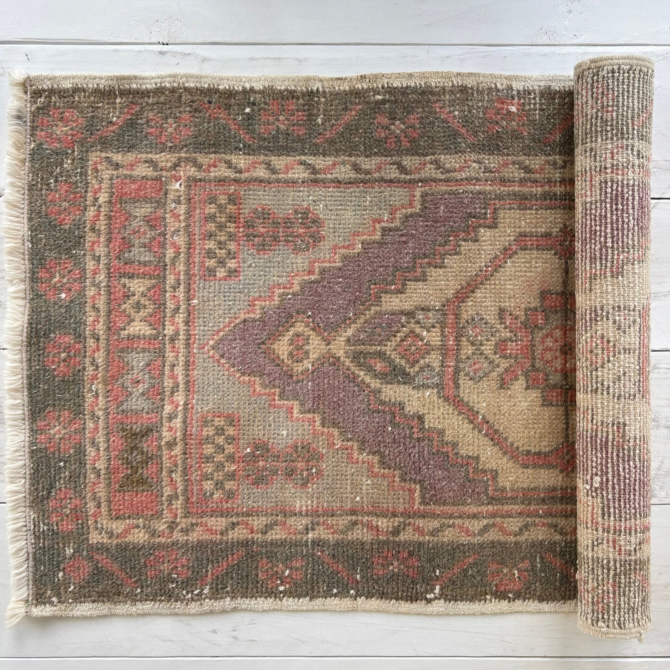 Rolling out a patterned rug on a light wooden floor