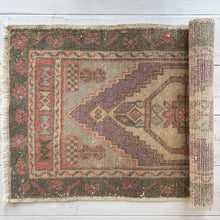 Load image into Gallery viewer, Rolling out a patterned rug on a light wooden floor