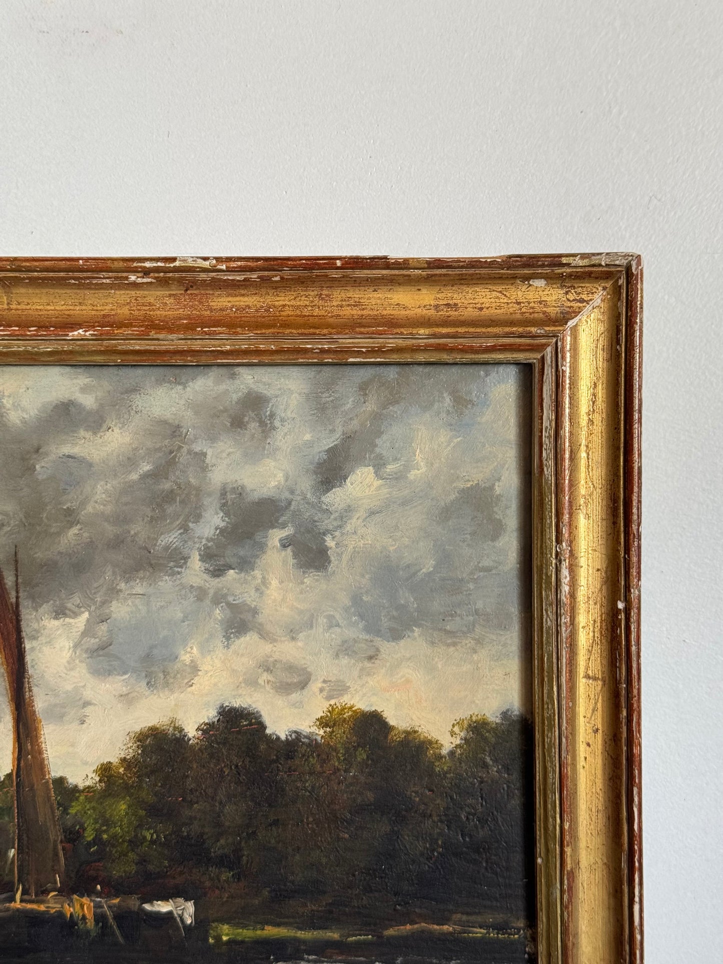 Framed painting of a landscape with trees and a cloudy sky.