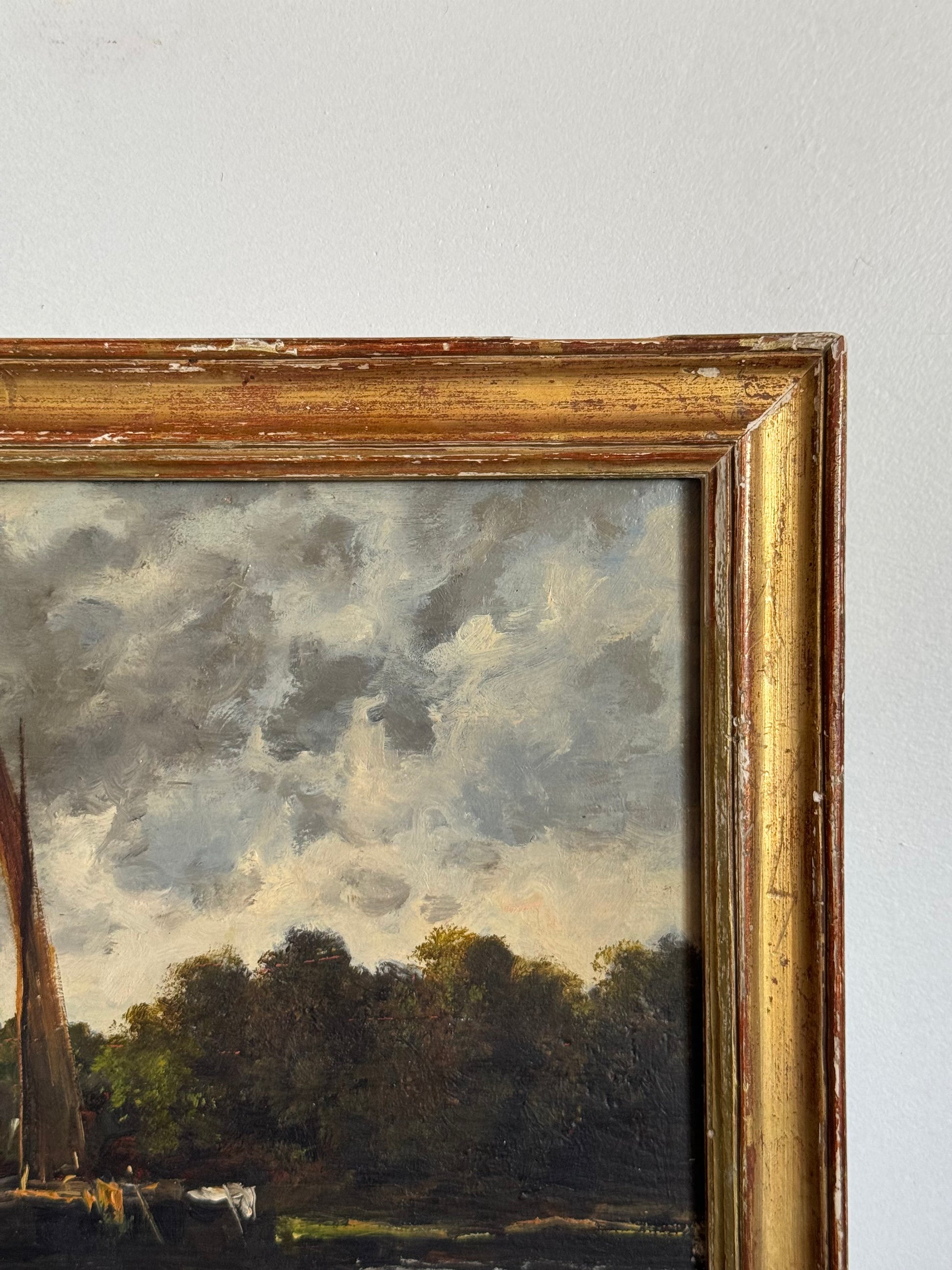 Framed painting of a landscape with trees and a cloudy sky.