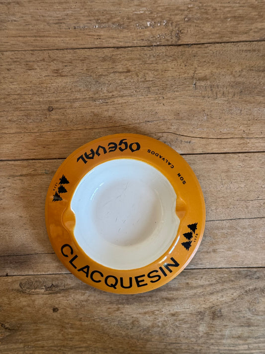 Round white catch all dish with a yellow border on a wooden surface