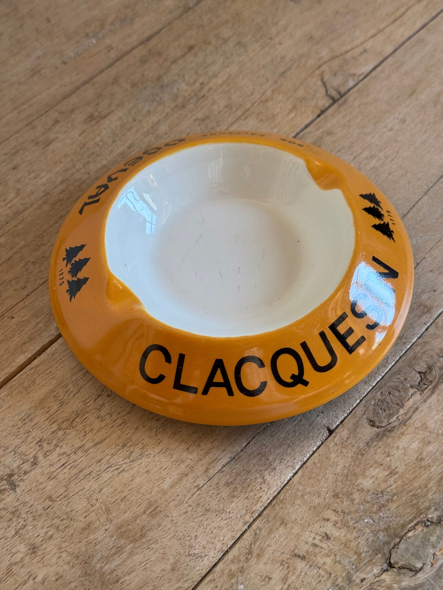 Yellow catch all dish with 'CLACQUE' branding on a wooden surface
