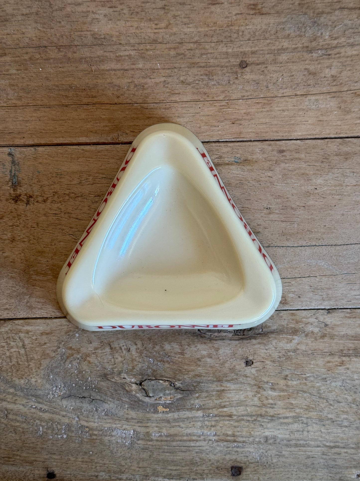 Triangular ceramic dish with red patterns on a wooden surface