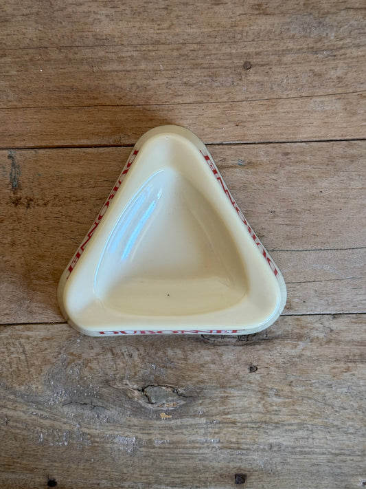 Triangular ceramic dish with red patterns on a wooden surface