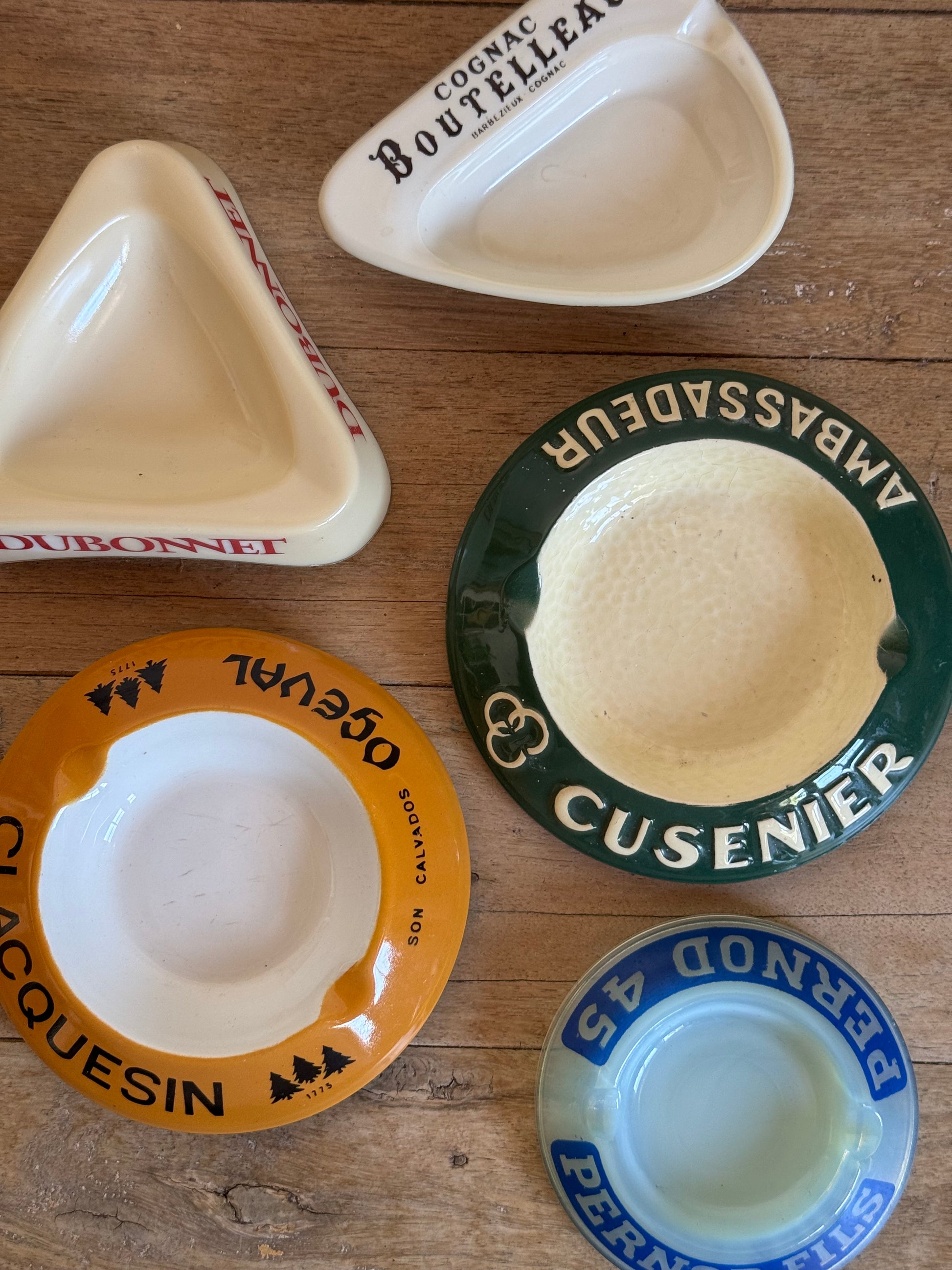 Collection of ceramic  catch all dishes with brand names on a wooden surface