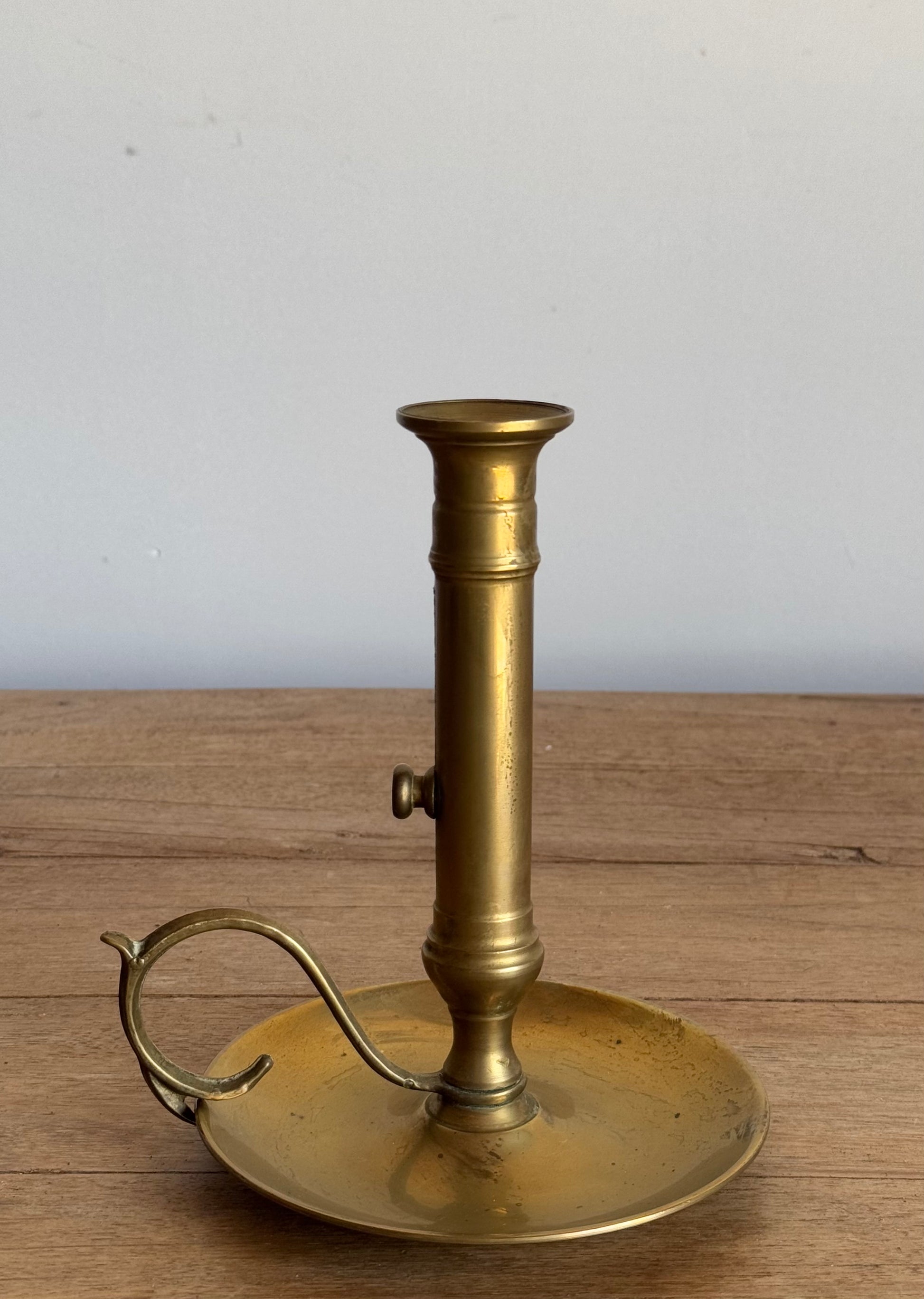 Brass candlestick holder on a wooden surface with a white background